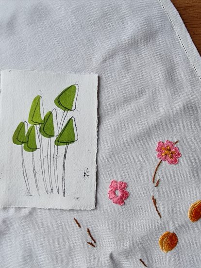 green ink drawing with monoprint of mushrooms on a vintage tablecloth